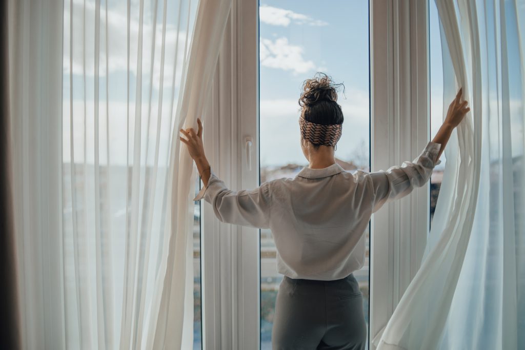 mujer abriendo las cortinas